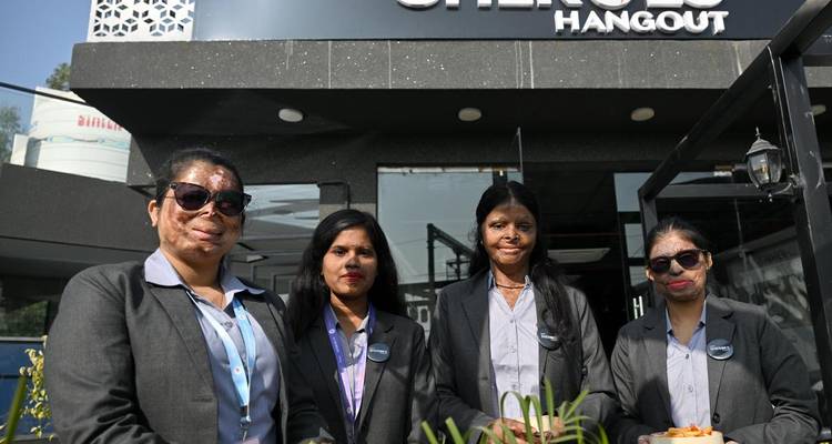 Four women in business suits standing proudly outside the SheRoes Hangout café.