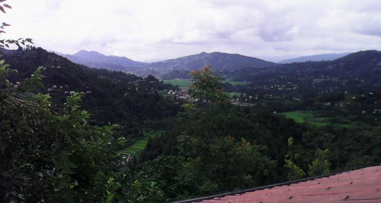 Heuvelachtig landschap met een uitzicht op een dorp in de verte en een dak.
