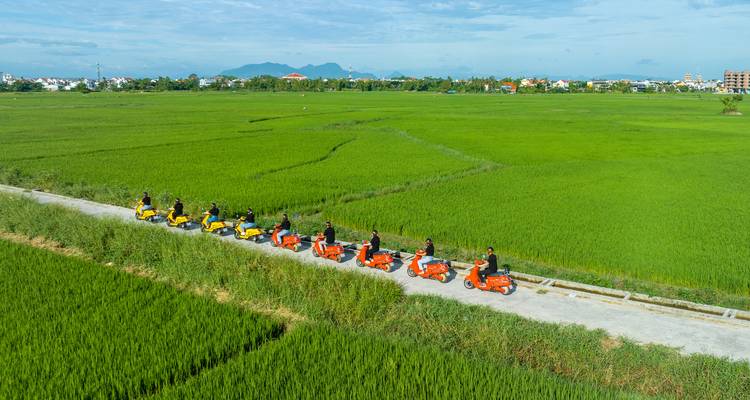 Gruppe von Menschen auf Rollern entlang einer Landstraße.