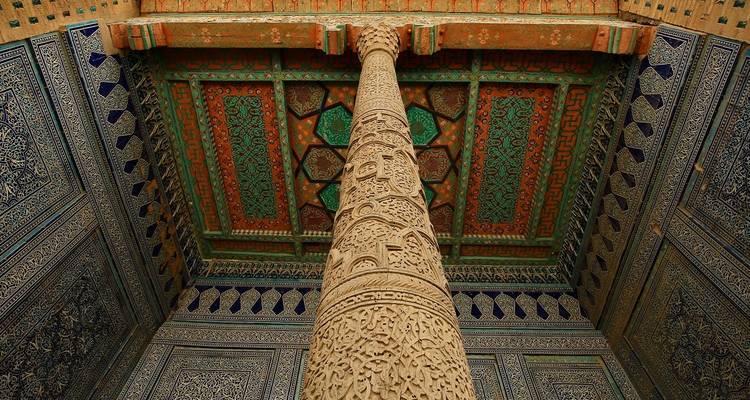 Ingewikkelde ontwerpen van een gebeeldhouwde zuil en beschilderd plafond.