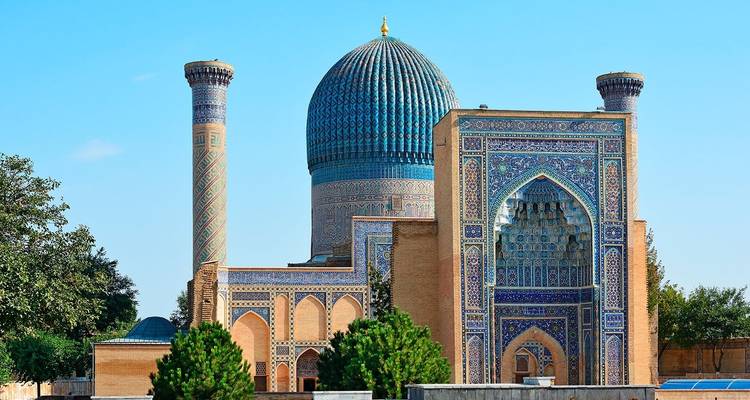 Een historisch, ingewikkeld betegeld gebouw met een grote blauwe koepel en twee minaretten.
