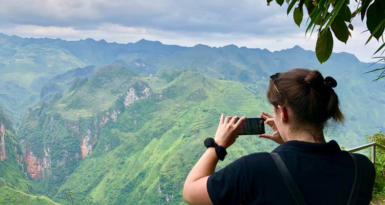 Reiziger maakt een smartphonefoto van dramatische groene bergen en diepe dalen vanaf een hoog uitkijkpunt
