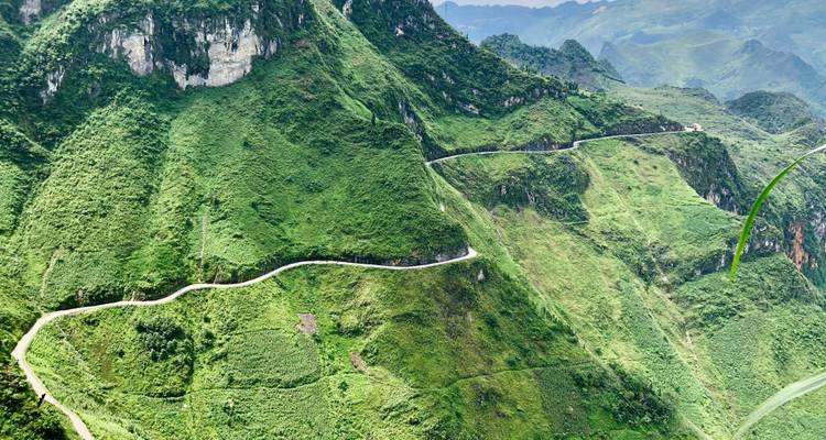 Slangachtige bergweg die zich een weg baant door steile groene bergkammen in afgelegen hoogland