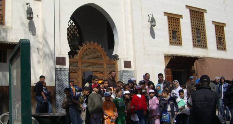 Groupe de personnes debout devant un bâtiment traditionnel.