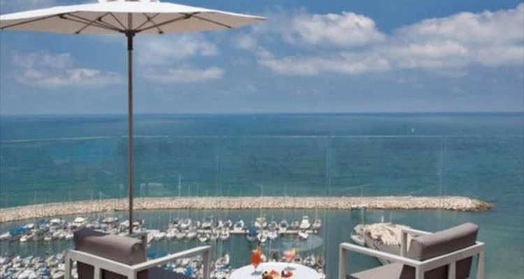 Outdoor dining area overlooking a marina and the sea.