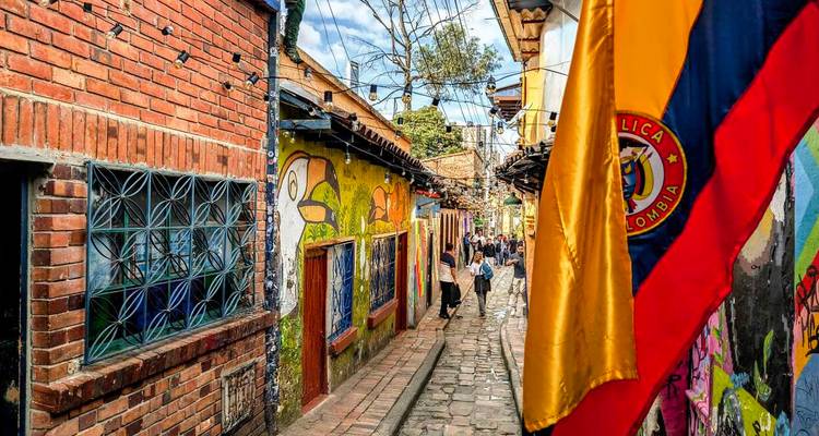 Calle vibrante con murales y bandera colombiana.
