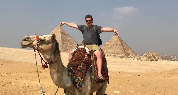 Reisender auf einem Kamel vor den Pyramiden an einem sonnigen Wüstentag