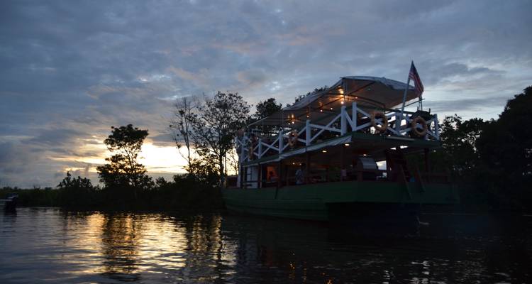 Bateau avec des lumières sur une rivière pendant le coucher de soleil.