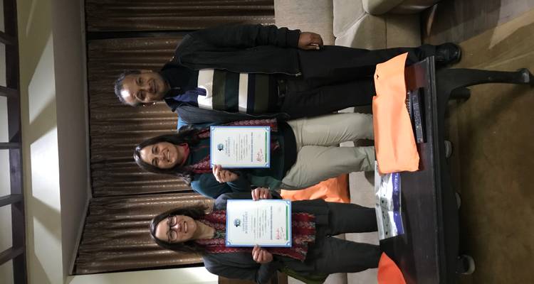 Deux personnes tenant des certificats avec un homme au milieu.