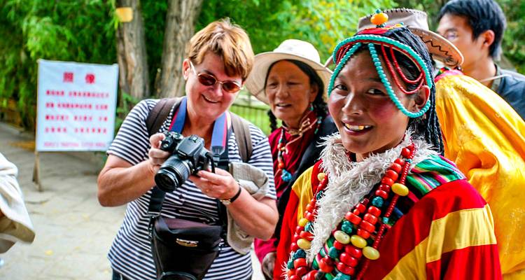 Turistas interactuando con una mujer local en vestimenta tradicional.