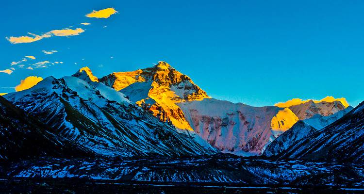 Montaña majestuosa al amanecer con luz dorada sobre picos nevados.