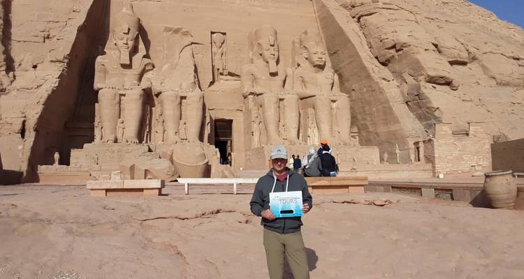 Persona sosteniendo un cartel de tour frente al Templo de Abu Simbel.