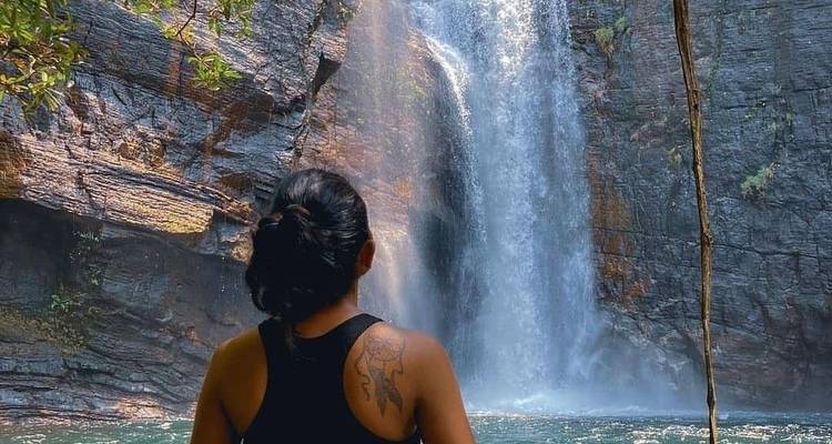 Person enjoying a view of a waterfall in a serene setting.
