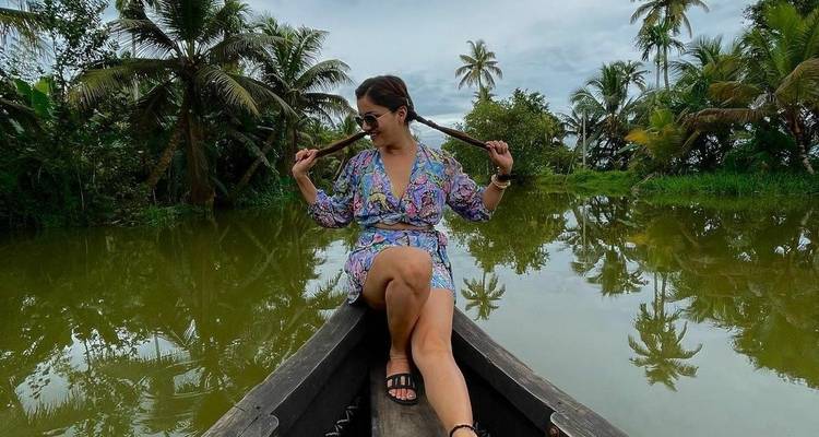 Woman sitting on a canoe in a tropical lagoon with palm trees.