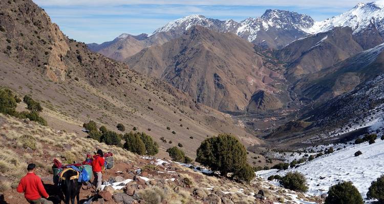 Wandelaars in een bergachtig landschap met sneeuwvlekken.