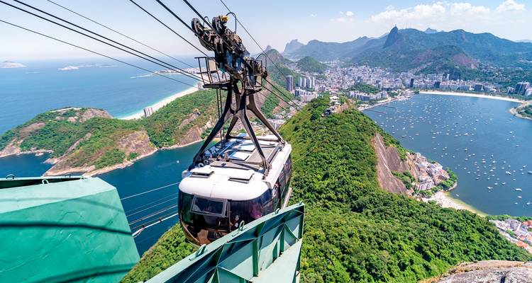 Teleférico ascendiendo a través de montañas exuberantes con vista a Río.