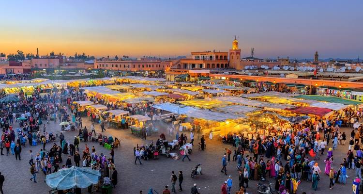Place Jemaa el-Fnaa animée au coucher du soleil avec des étals de marché à Marrakech.