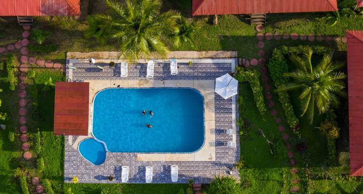 Vista aérea de una piscina serena con vegetación circundante y estructuras del resort.