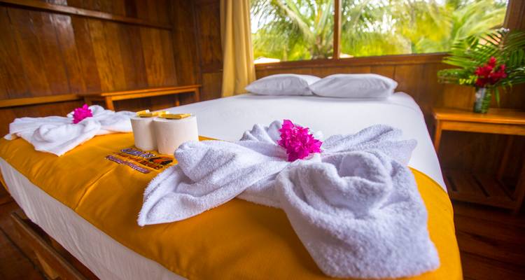 Una cama de hotel pulcramente decorada with toallas dobladas y flores.