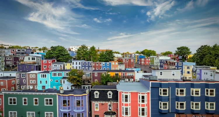 Une vue panoramique de maisons mitoyennes aux couleurs vives sous un ciel bleu dramatique à Saint-Jean.