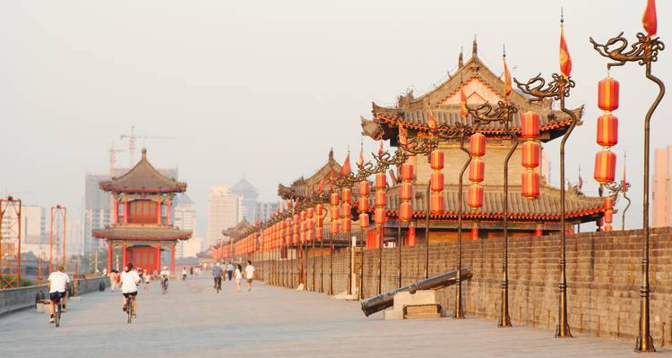 Ancient Xi'an city wall lined with red lanterns in warm evening light with cyclists and walkers