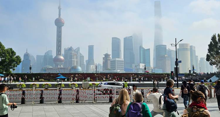 Skyline of Shanghai's Pudong district rising behind the Bund promenade crowded with visitors