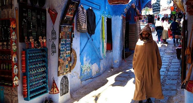 Un hombre caminando por un callejón azul vibrante con tiendas.