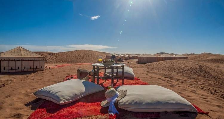 Campamento del desierto con asientos y cojines bajo un cielo despejado.