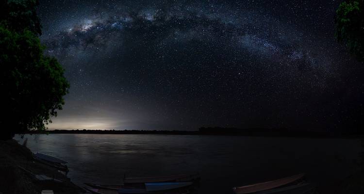 Cielo nocturno con estrellas sobre una masa de agua tranquila.