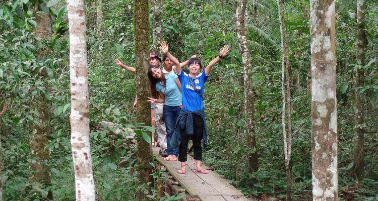 Grupo de personas haciendo un gesto de saludo con la mano en un sendero de la selva.