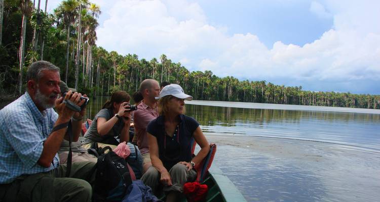 Grupo de personas en un barco en un lago con palmeras.