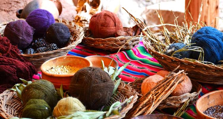 Bunte Wollknäuel und traditionelle Webmaterialien, die auf einem lebendigen Stoff ausgestellt sind.