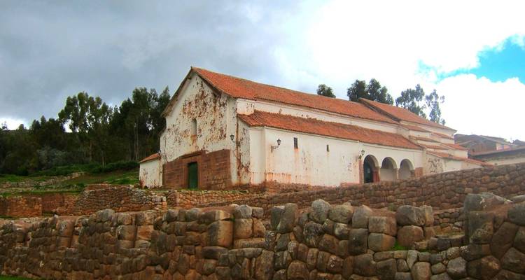 Historisches Gebäude mit Steinterrasse, bewölkter Himmel im Hintergrund.