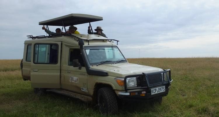 Groep mensen in een safariwagen in een open veld.