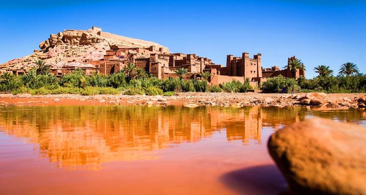 Vista de una kasbah histórica reflejada en un río.