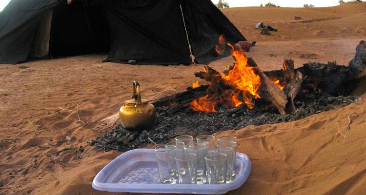 Thee-opstelling bij een kampvuur in een woestijnomgeving.