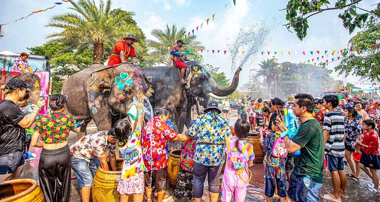 Personas celebrando con elefantes durante un festival de agua con colores vibrantes.