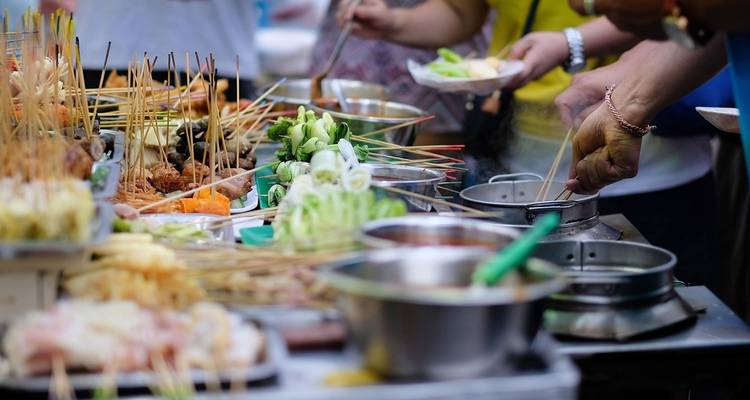 Vielfalt von Straßenessen mit Leuten, die kochen und servieren.