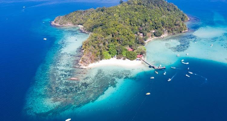 Luftaufnahme einer Insel mit klarem blauen Wasser und Booten.