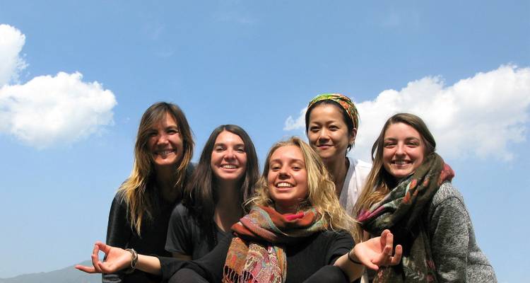 A group of five friends smiling and posing against a clear blue sky.