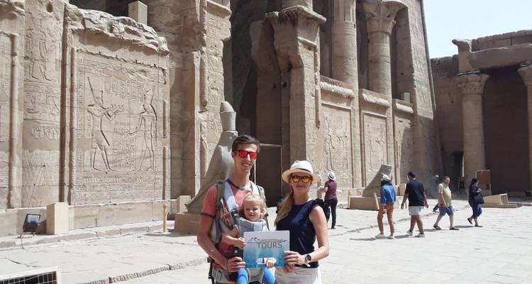 Familie posiert mit einem Schild vor einem antiken Tempel.
