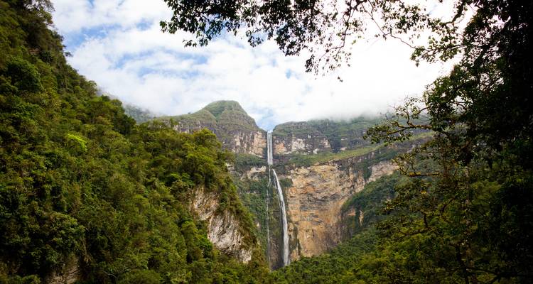 A waterfall with misty cliffs surrounded by greenery.