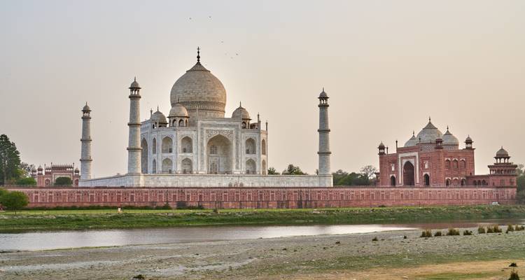 Das Taj Mahal jenseits eines Flusses, unter weichem Sonnenuntergangslicht.