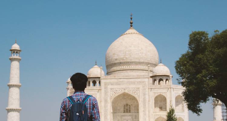 Persoon die naar de Taj Mahal kijkt met heldere blauwe luchten.