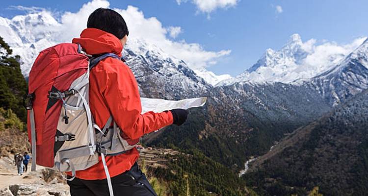 Wanderer liest eine Karte mit schneebedeckten Bergen im Hintergrund.