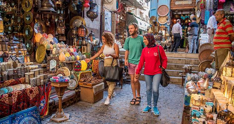 Petit groupe parcourant des étals de lanternes colorées et de poterie dans un étroit bazar du Moyen-Orient