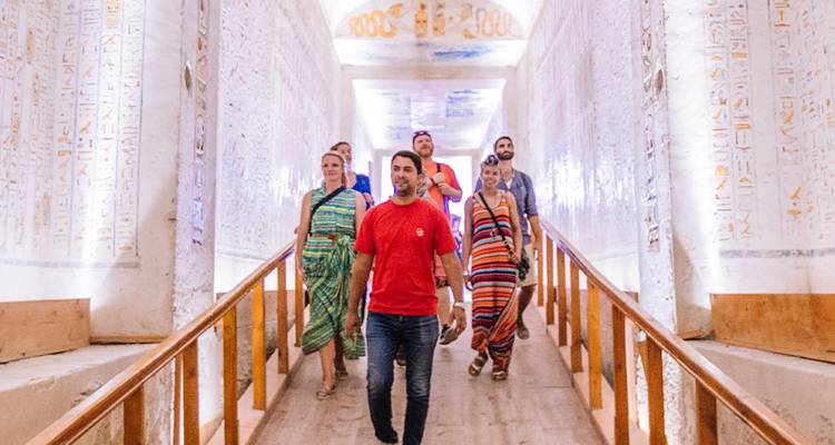 Groupe marchant dans un couloir orné d'inscriptions à l'intérieur d'une tombe égyptienne antique