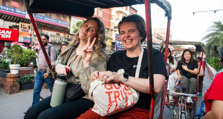 Toeristen die genieten van een riksja-rit door een drukke marktstraat.