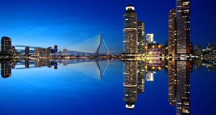 Una vista nocturna de un paisaje urbano moderno con edificios iluminados y un puente.