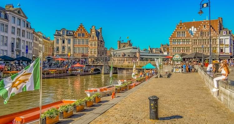 Een drukke gracht met mensen die langs het water dineren, nabij oude gebouwen.
